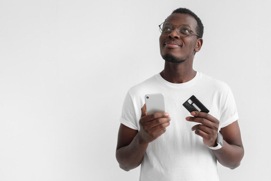 Young African male in eyeglasses holding a credit card.