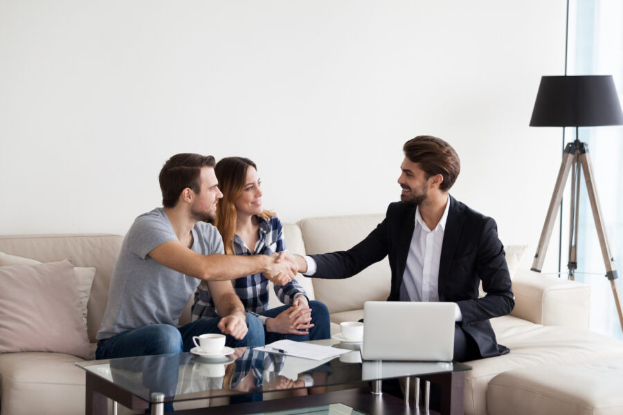 Young couple shaking hands with a real estate agent to obtain a professional mortgage.