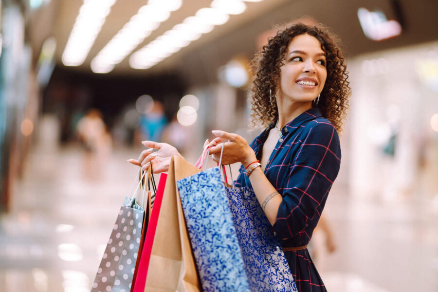 Young smiling woman holding holiday shopping bags.
