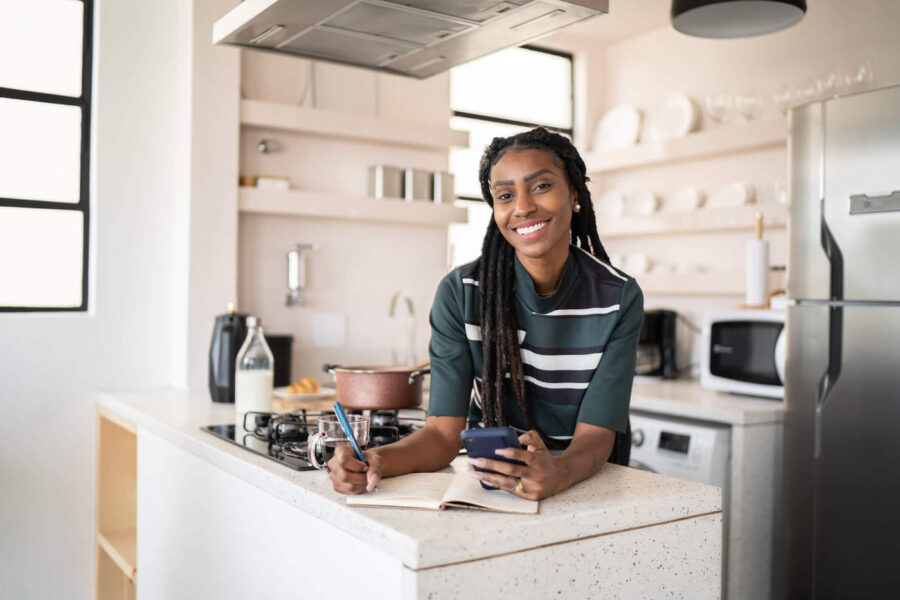 Young smiling woman on kitchen counter researching how to get loan for land.