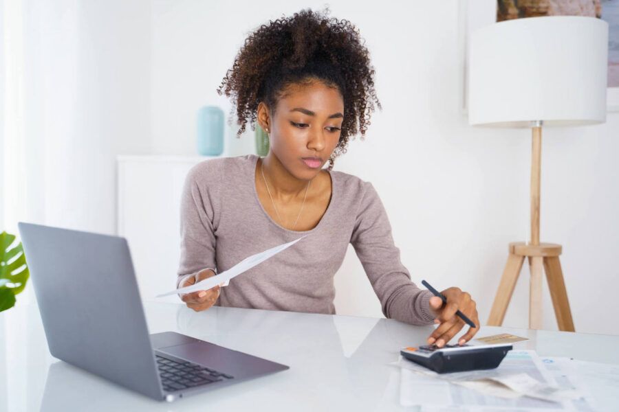 Young woman calculating loan amounts with calculator.