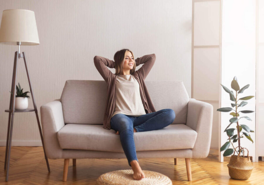 Young woman happily seated on sofa of new place.